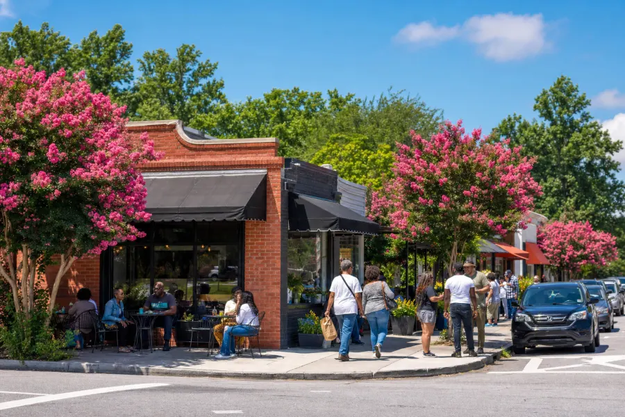 A friendly commercial corner in southwest Atlanta with brick storefronts and neighbors chatting on the sidewalk in evening light.